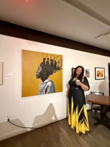 Myja Lark standing in front of her piece, Ohemaa.