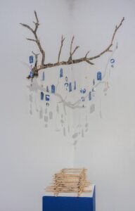 Blue and white charms hanging from a dried cholla branch.